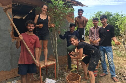 A volunteer group planting a tree and smiling.